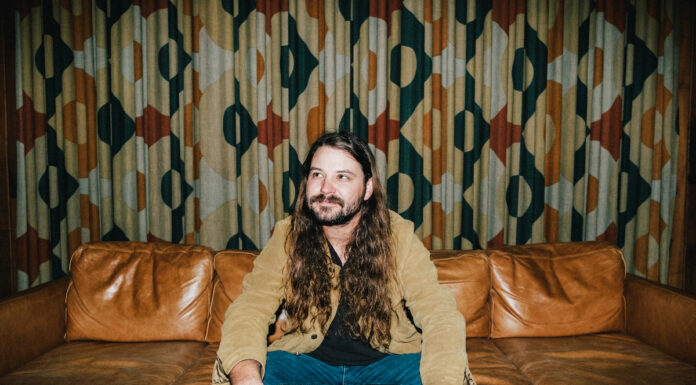 Brent Cobb hosts 2nd South of Atlanta Fest at Robins Financial Capitol Theatre Brent Cobb sits on a leather couch in front of patterned curtains.