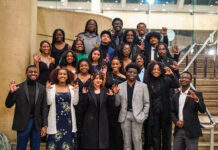 Want to jumpstart your career? Attend a national convention A group of Mercer University students pose on stairs indoors, dressed formally and making a claw gesture with their hands.