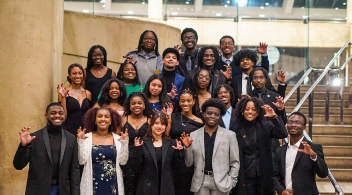Want to jumpstart your career? Attend a national convention A group of Mercer University students pose on stairs indoors, dressed formally and making a claw gesture with their hands.