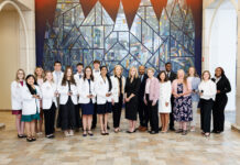 School of Medicine celebrates 2026 Children’s Healthcare of Atlanta Rural Scholars A group of people, some in white coats, stand together indoors in front of a large, geometric stained glass mural.