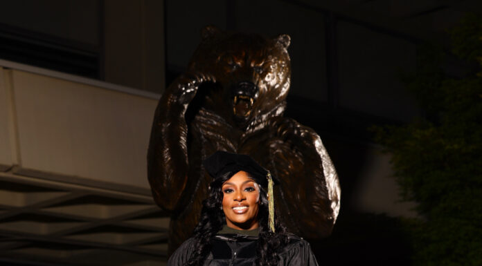 Graduate Spotlight: Deandra Bradley Deandra Bradley, wearing graduation attire, stands in front of a bear statue.