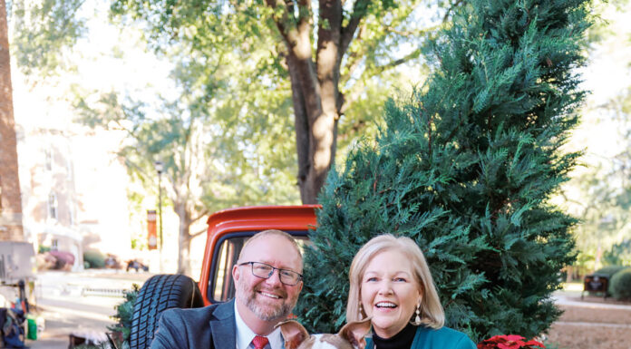 Meet Mercer’s new First Dog: Champ Jason Elkins and Mercer President Dr. Penny L. Elkins sit with a dog in the back of a red truck decorated with Christmas trees and blankets.