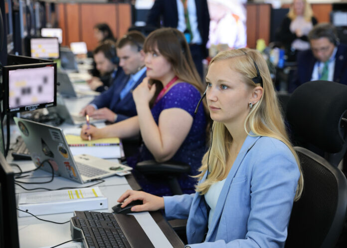 Me at the console in the firing room on launch day, monitoring our system and performing functional checkouts prior to the launch Several people sit at desks working on computers in an office setting, focused on their monitors.