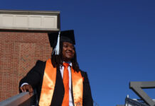 Graduate Spotlight: Nicholas Milsap Nicholas Milsap in cap and gown stands on outdoor steps, wearing an orange sash and matching tie and sneakers.