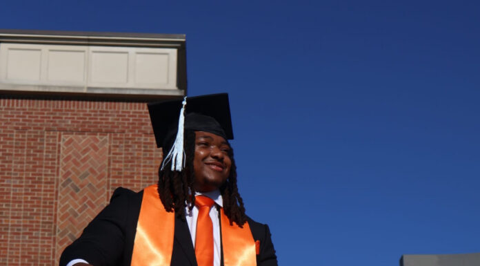 Graduate Spotlight: Nicholas Milsap Nicholas Milsap in cap and gown stands on outdoor steps, wearing an orange sash and matching tie and sneakers.