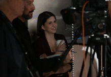 Mercer alumna helps share NASA’s Artemis II story with the world Katie Konans smiles while standing behind a camera setup with two other people at an indoor event.