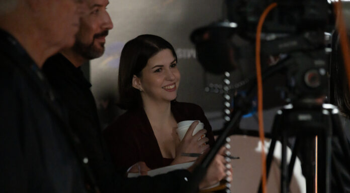 Mercer alumna helps share NASA’s Artemis II story with the world Katie Konans smiles while standing behind a camera setup with two other people at an indoor event.