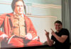 Theology student weaves storytelling into pastoral, historical work Smiling man points at a projected image of an actor in historical costume on a screen.
