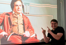 Theology student weaves storytelling into pastoral, historical work Smiling man points at a projected image of an actor in historical costume on a screen.