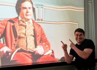 Theology student weaves storytelling into pastoral, historical work Smiling man points at a projected image of an actor in historical costume on a screen.