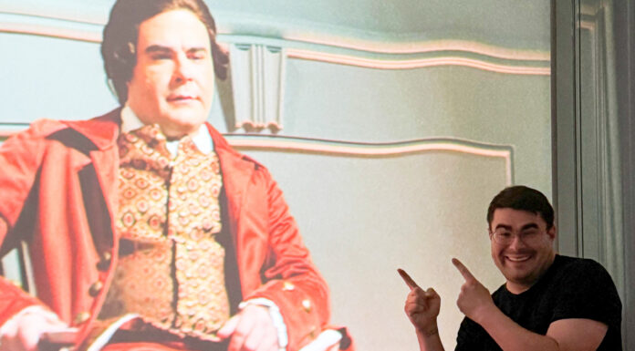 Theology student weaves storytelling into pastoral, historical work Smiling man points at a projected image of an actor in historical costume on a screen.