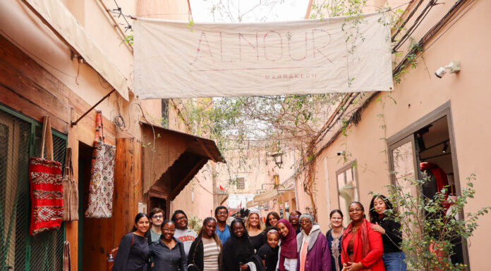 Morocco trip opens students’ eyes to international health interventions A group of people pose together in an outdoor hallway beneath a large banner reading Alnour Marrakech.