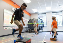Professor studies impact of physical activity on attention in kids with dyslexia Three boys participate in physical activities in a classroom with exercise equipment and a trampoline in the background.