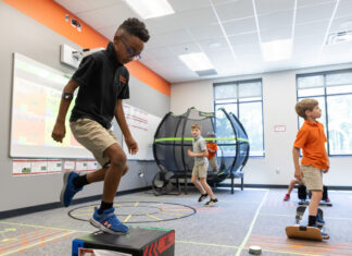 Professor studies impact of physical activity on attention in kids with dyslexia Three boys participate in physical activities in a classroom with exercise equipment and a trampoline in the background.