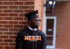 Graduate Spotlight: Deon Brown A man in a graduation cap and Mercer University sweatshirt leans against a brick wall outdoors.