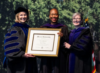 Mercer Law confers honorary Doctor of Laws degree upon the Hon. Erica L. Woodford Three women in academic regalia hold a framed Mercer University diploma at a graduation ceremony.
