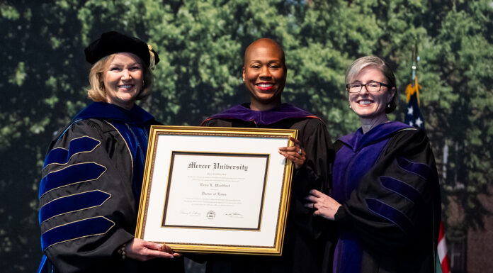 Mercer Law confers honorary Doctor of Laws degree upon the Hon. Erica L. Woodford Three women in academic regalia hold a framed Mercer University diploma at a graduation ceremony.