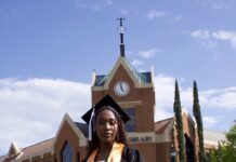 Graduate Spotlight: Olivia Harris Olivia Harris in cap and gown stands on grass in front of Tarver Library.
