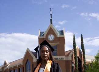 Graduate Spotlight: Olivia Harris Olivia Harris in cap and gown stands on grass in front of Tarver Library.