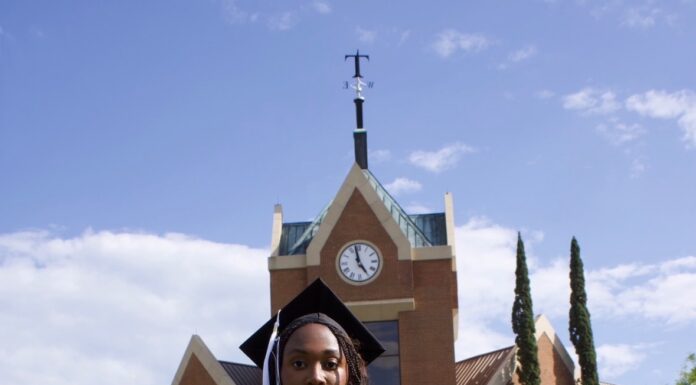 Graduate Spotlight: Olivia Harris Olivia Harris in cap and gown stands on grass in front of Tarver Library.