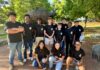 Education alumna brings middle schoolers to Mercer campus for robotics contest A group of students in matching black shirts poses in front of a bear statue outdoors on a sunny day.