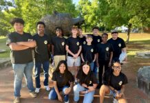 Education alumna brings middle schoolers to Mercer campus for robotics contest A group of students in matching black shirts poses in front of a bear statue outdoors on a sunny day.