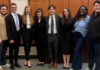 Mercer Law advocacy rises to No. 3 nationally in Gavel Rankings Eight people stand side by side indoors, dressed in business and casual attire, smiling toward the camera.