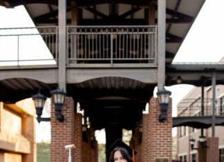 Graduate Spotlight: Samanta Schultz Samanta Schultz wears graduation attire and stands outdoors, holding a hammer and smiling at the camera.