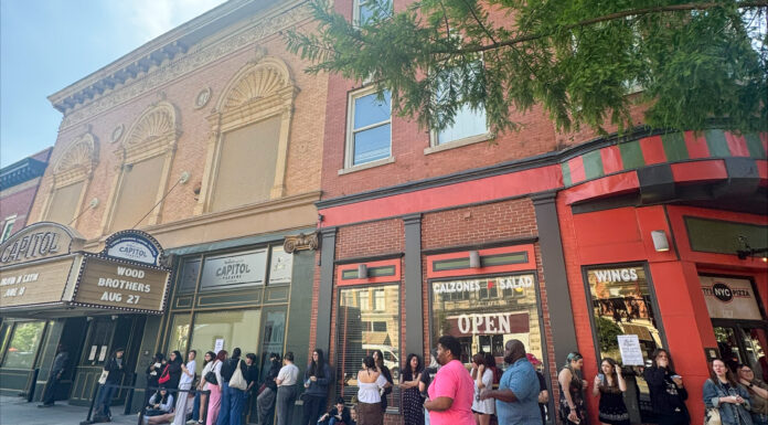 Phoebe Bridgers brings secret show to Mercer’s Robins Financial Capitol Theatre A group of people waits in line outside a theater and nearby restaurants on a city sidewalk.