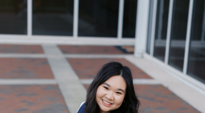Graduate Spotlight: Cathy Le Woman in a white dress kneeling on brick pavement, holding a bouquet, wearing a sash that reads Vice President.