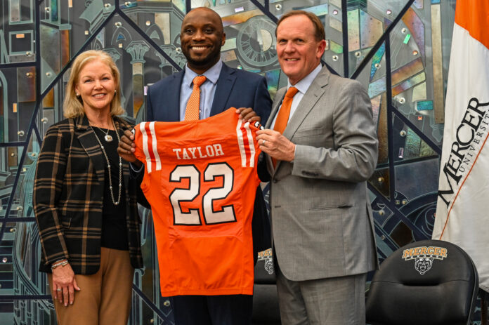 President Dr. Penny L. Elkins, Joel Taylor and Jim Cole pose indoors as Joel Taylor holds a Mercer University football jersey labeled Taylor 22.