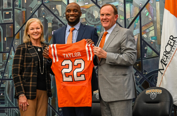 President Dr. Penny L. Elkins, Joel Taylor and Jim Cole pose indoors as Joel Taylor holds a Mercer University football jersey labeled Taylor 22.