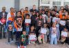 Professor earns EXPy Award for computer science initiatives at home and abroad A large group of children and adults pose together outside a building, holding certificates and wearing matching shirts.