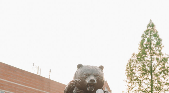 Graduate Spotlight: Pariss Nicholson Pariss Nicholson in cap and gown poses playfully with a microphone in front of the bear statue at Mercer.