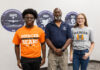 Engineering alumnus helps keep Air Force aircraft flying Three people stand indoors in front of wall signs, two wearing Mercer University shirts and one in a navy polo.