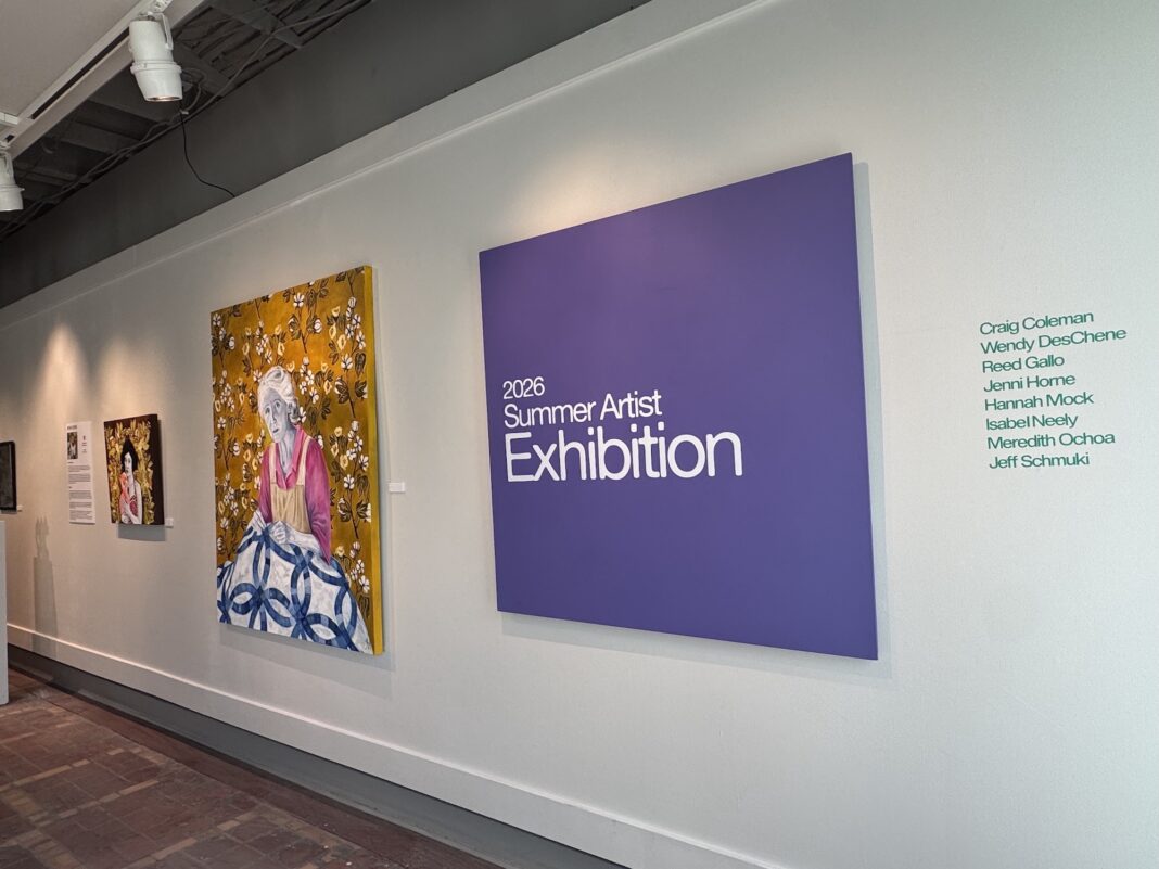 IMG_7485 A gallery wall displays art and a large purple sign reading 2026 Summer Artist Exhibition with a list of artists names.
