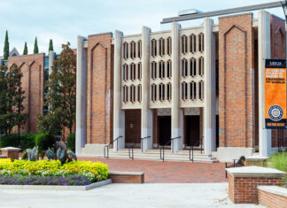 Mercer team develops innovative tools for analyzing climate data Brick building with three entrances, decorative façade, and flowerbeds in front; orange banner on the right.