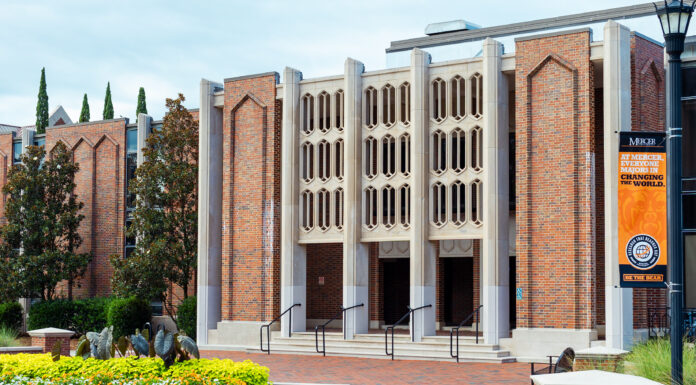 Mercer team develops innovative tools for analyzing climate data Brick building with three entrances, decorative façade, and flowerbeds in front; orange banner on the right.