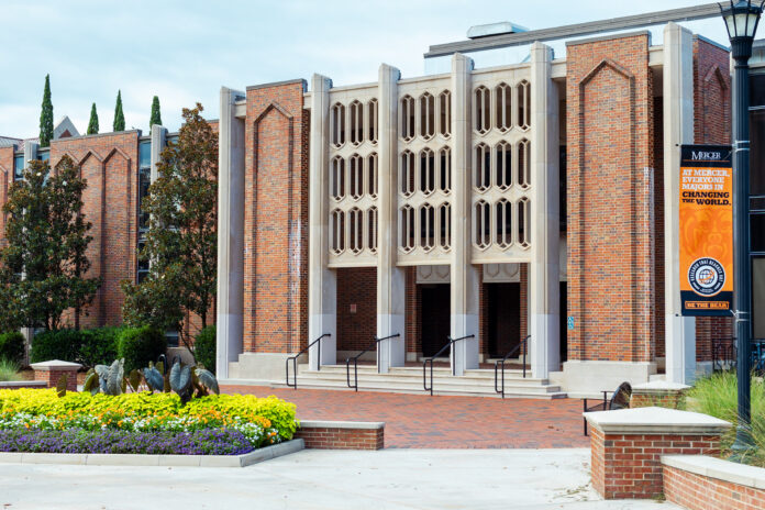 StetsonHallKL23 Brick building with three entrances, decorative façade, and flowerbeds in front; orange banner on the right.