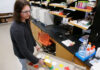 Mercer professors develop international standard for detecting lead in new paint Person in safety glasses uses a handheld device to scan paint samples on a cart in a laboratory setting.