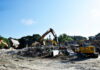 Building for BEARS project advances with demolition of Connell Student Center Excavators clearing debris and rubble at a building demolition site under a clear blue sky.