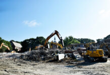 Building for BEARS project advances with demolition of Connell Student Center Excavators clearing debris and rubble at a building demolition site under a clear blue sky.