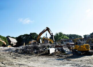 Building for BEARS project advances with demolition of Connell Student Center Excavators clearing debris and rubble at a building demolition site under a clear blue sky.