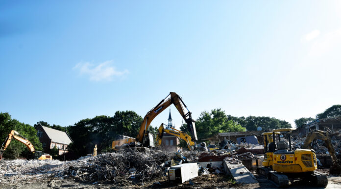 Building for BEARS project advances with demolition of Connell Student Center Excavators clearing debris and rubble at a building demolition site under a clear blue sky.