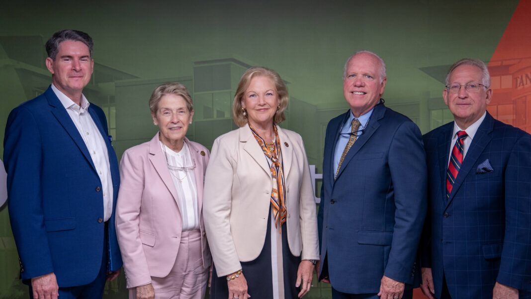 Carrollton Mercer leadership Five professionally dressed adults stand side by side against a green and red backdrop, facing the camera.