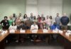 Mercer helps teachers bring student-centered discussions to their classrooms A group of adults pose for a photo in a conference room, seated and standing around wooden tables with nameplates.