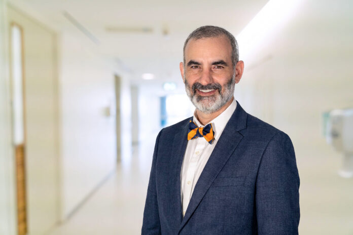 Dr. Matt Varn Dr. Matt Varn in a blue suit and bow tie standing and smiling in a brightly lit hallway.