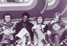 Alan Walden’s influence reached from Mercer to Macon and beyond Four men sitting on a patterned couch in front of a geometric backdrop, all facing the camera and smiling.
