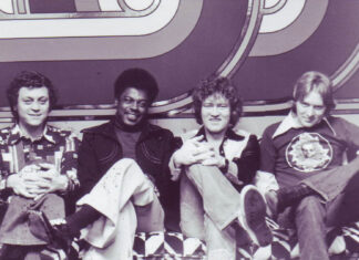 Alan Walden’s influence reached from Mercer to Macon and beyond Four men sitting on a patterned couch in front of a geometric backdrop, all facing the camera and smiling.