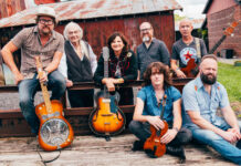 Amy Ray of Indigo Girls kicks off Mercer series exploring Southern music Seven people with musical instruments pose outdoors in front of a rustic barn and metal fence.